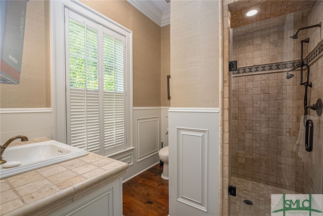 bathroom with a shower with door, ornamental molding, hardwood / wood-style flooring, toilet, and vanity