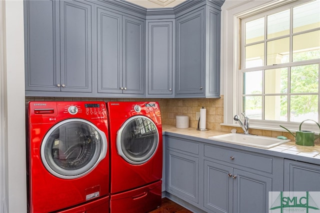 clothes washing area featuring dark wood-type flooring, sink, cabinets, and washing machine and dryer