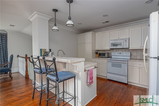 kitchen with white appliances, dark wood-type flooring, crown molding, and a kitchen bar