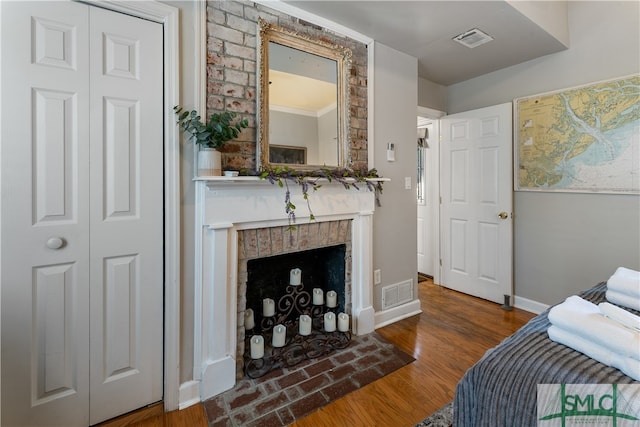 bedroom featuring ornamental molding, a fireplace, and dark wood-type flooring