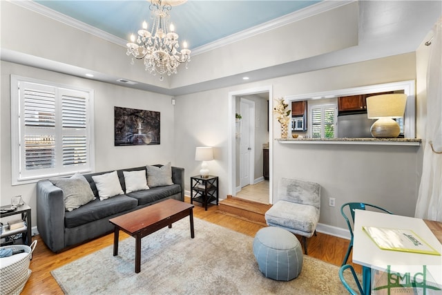 living room with a raised ceiling, light wood-type flooring, and a chandelier