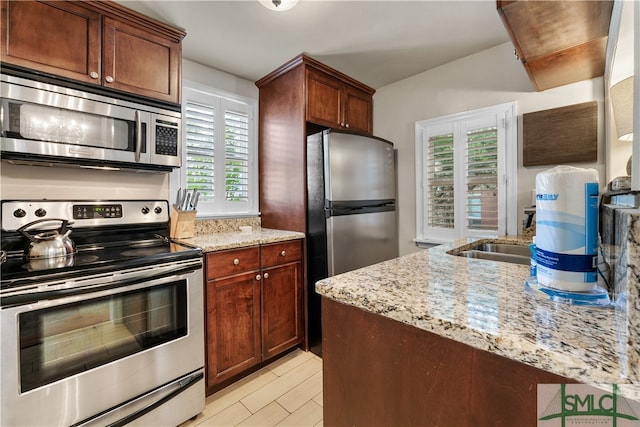 kitchen with appliances with stainless steel finishes, sink, and light stone countertops