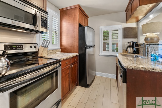 kitchen with appliances with stainless steel finishes, sink, and light stone counters