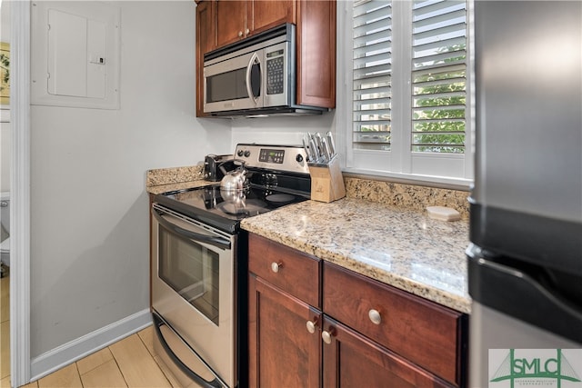 kitchen with light hardwood / wood-style flooring, stainless steel appliances, and light stone countertops