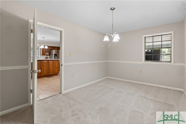 carpeted spare room featuring an inviting chandelier