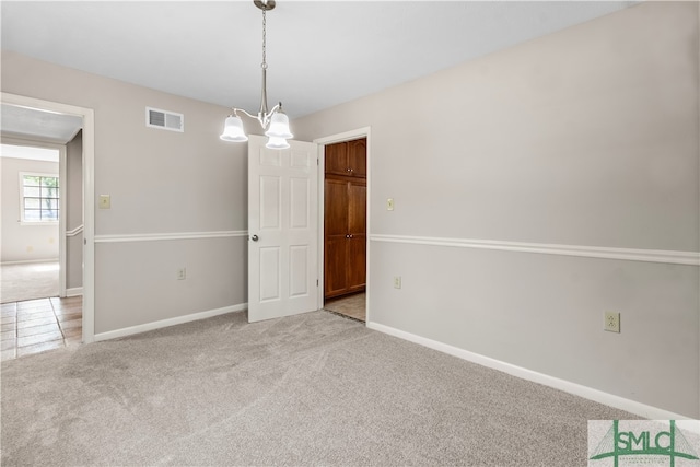 carpeted empty room with a notable chandelier