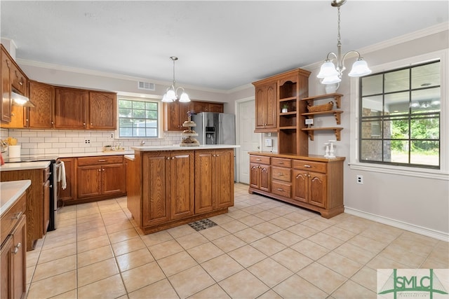 kitchen with decorative backsplash, appliances with stainless steel finishes, pendant lighting, an inviting chandelier, and a center island