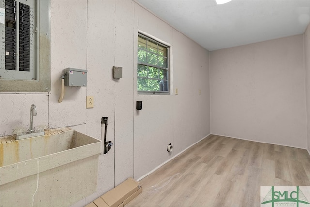 laundry area with light hardwood / wood-style floors and sink