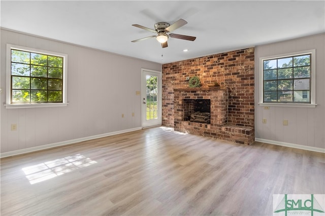 unfurnished living room with a fireplace, ceiling fan, and light hardwood / wood-style flooring