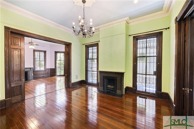 unfurnished living room with ceiling fan with notable chandelier, crown molding, and dark wood-type flooring