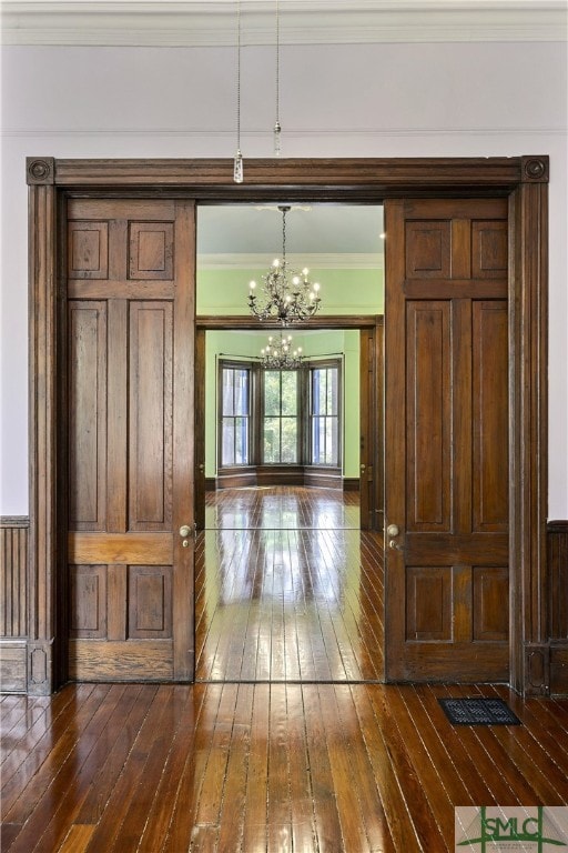 corridor with an inviting chandelier, dark hardwood / wood-style flooring, and crown molding