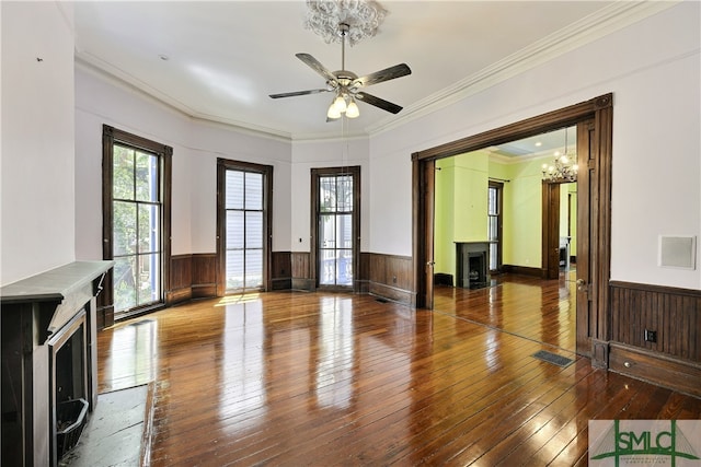 unfurnished room featuring ceiling fan with notable chandelier, crown molding, and hardwood / wood-style flooring