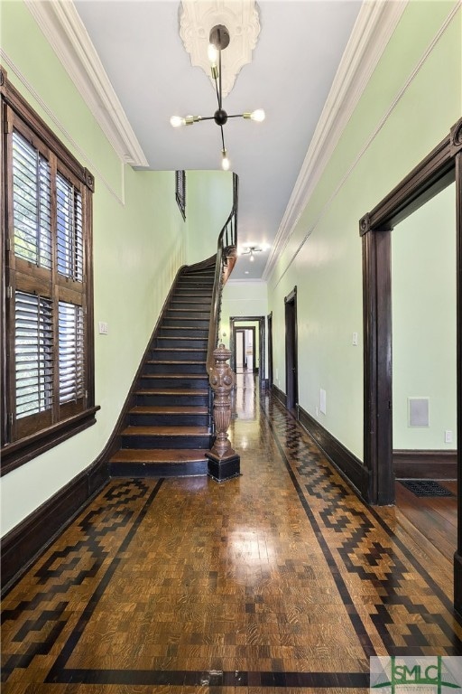 staircase with an inviting chandelier, wood-type flooring, and crown molding