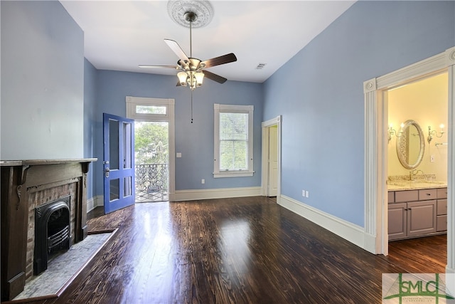 unfurnished living room with dark wood-type flooring, ceiling fan, sink, and a fireplace