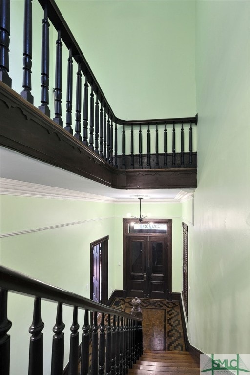 staircase featuring hardwood / wood-style floors, crown molding, and a high ceiling