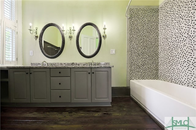 bathroom with dual sinks, wood-type flooring, and vanity with extensive cabinet space