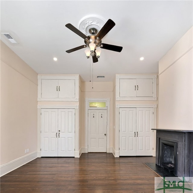 unfurnished living room featuring ceiling fan and dark wood-type flooring