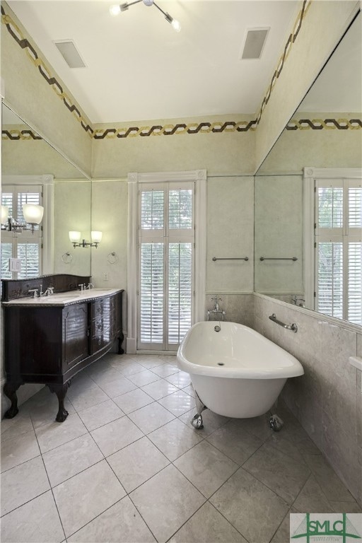 bathroom featuring tile walls, vanity, a bathtub, and tile flooring