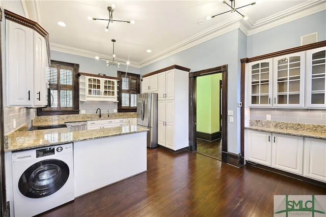 kitchen featuring dark hardwood / wood-style floors, tasteful backsplash, washer / clothes dryer, stainless steel refrigerator, and ornamental molding