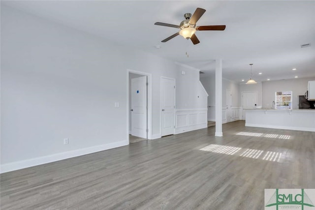 unfurnished living room featuring ceiling fan and hardwood / wood-style floors