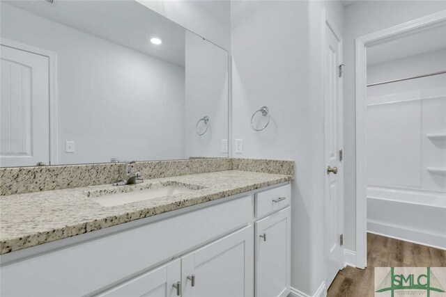 bathroom featuring hardwood / wood-style floors, vanity, and shower / bathtub combination