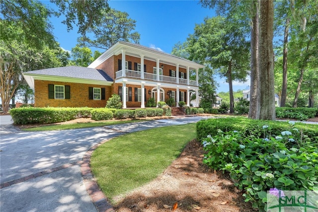 neoclassical home with a balcony and a front lawn