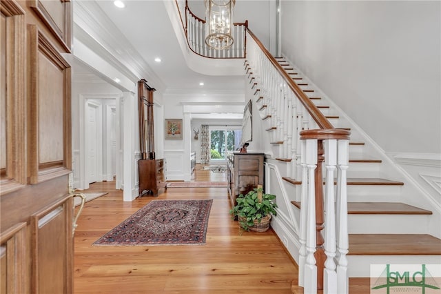 entryway featuring crown molding, light hardwood / wood-style floors, and a chandelier