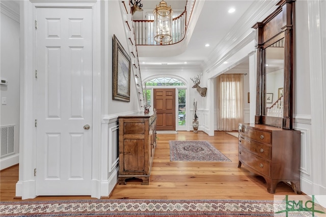 entryway featuring a notable chandelier, crown molding, and light wood-type flooring