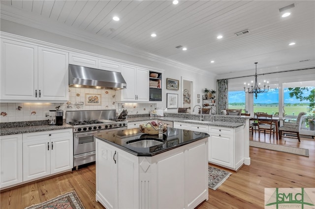 kitchen featuring light hardwood / wood-style flooring, kitchen peninsula, double oven range, wall chimney range hood, and white cabinetry