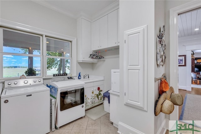 laundry area featuring cabinets, light tile flooring, washing machine and clothes dryer, crown molding, and sink