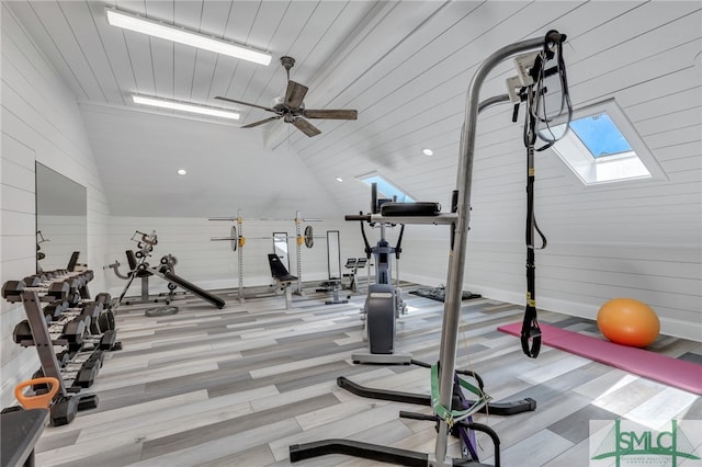 exercise area with high vaulted ceiling, ceiling fan, light hardwood / wood-style flooring, and a skylight