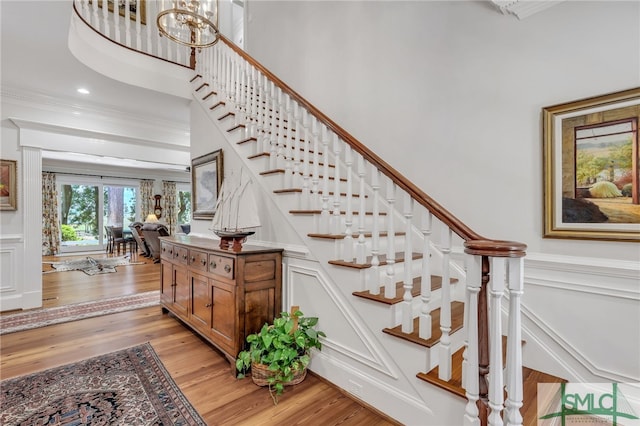 staircase with a high ceiling, crown molding, and light wood-type flooring