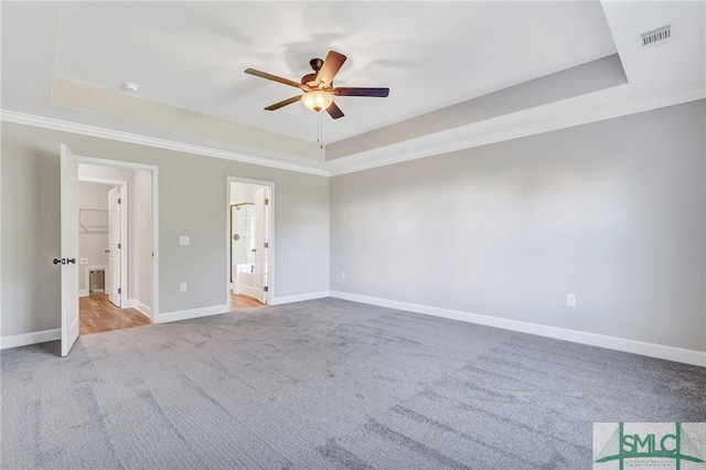 unfurnished bedroom featuring connected bathroom, ceiling fan, a tray ceiling, and light colored carpet