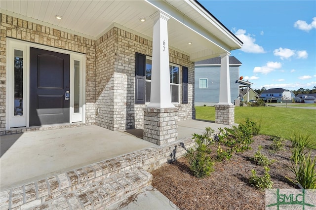 view of exterior entry with a porch and a lawn