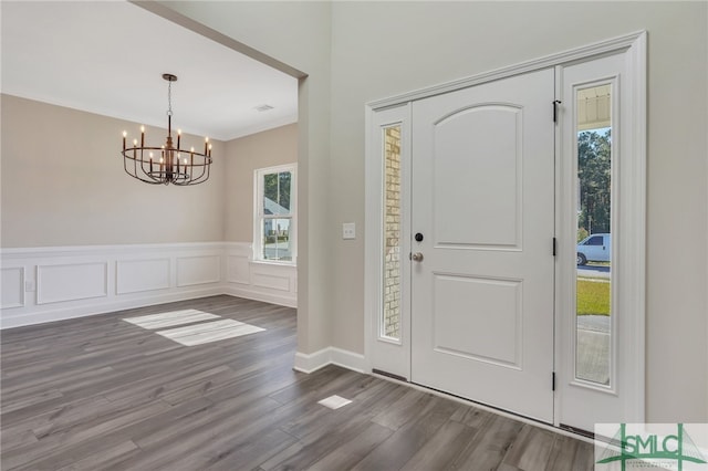 entrance foyer featuring ornamental molding, dark hardwood / wood-style floors, a chandelier, and a wealth of natural light