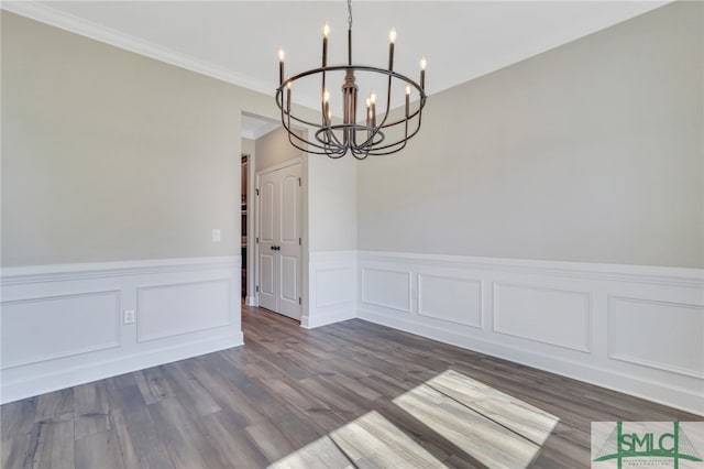 unfurnished dining area featuring ornamental molding, hardwood / wood-style flooring, and a chandelier