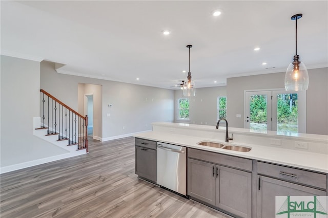 kitchen with light hardwood / wood-style flooring, dishwasher, sink, and decorative light fixtures