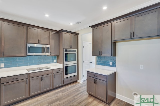 kitchen featuring decorative backsplash, dark brown cabinets, ornamental molding, appliances with stainless steel finishes, and light hardwood / wood-style floors