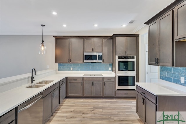 kitchen with stainless steel appliances, sink, crown molding, pendant lighting, and light wood-type flooring