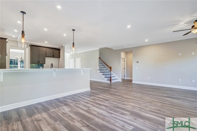 kitchen with hanging light fixtures, dark brown cabinets, ornamental molding, a kitchen bar, and light hardwood / wood-style floors