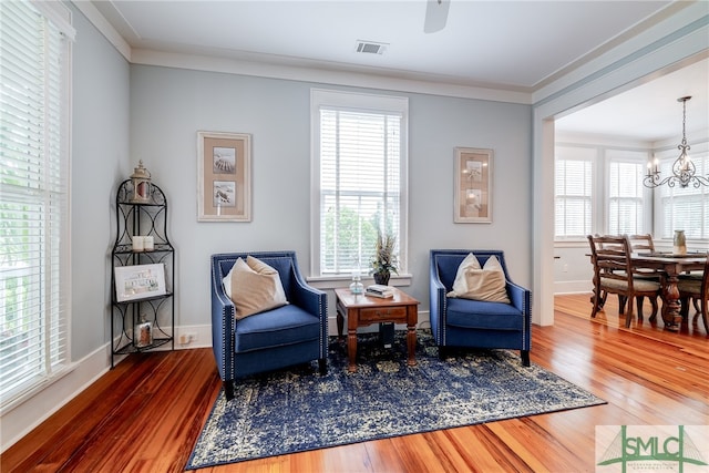 sitting room featuring a notable chandelier, ornamental molding, and dark hardwood / wood-style floors