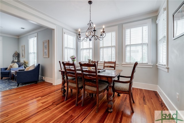 dining space featuring a healthy amount of sunlight, crown molding, hardwood / wood-style flooring, and a chandelier