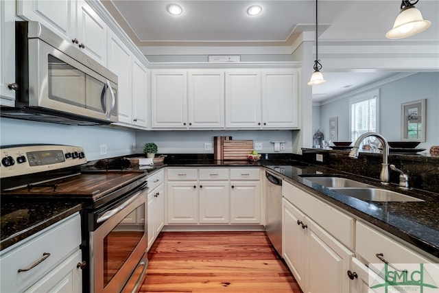 kitchen featuring decorative light fixtures, light hardwood / wood-style floors, white cabinetry, appliances with stainless steel finishes, and sink