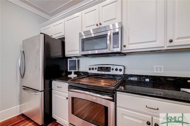 kitchen featuring hardwood / wood-style floors, stainless steel appliances, white cabinets, and dark stone countertops