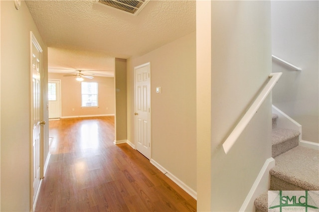 corridor with hardwood / wood-style flooring and a textured ceiling