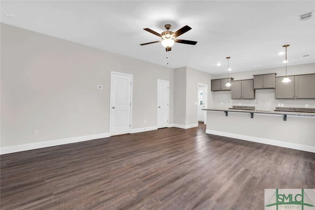 unfurnished living room featuring ceiling fan and dark hardwood / wood-style flooring