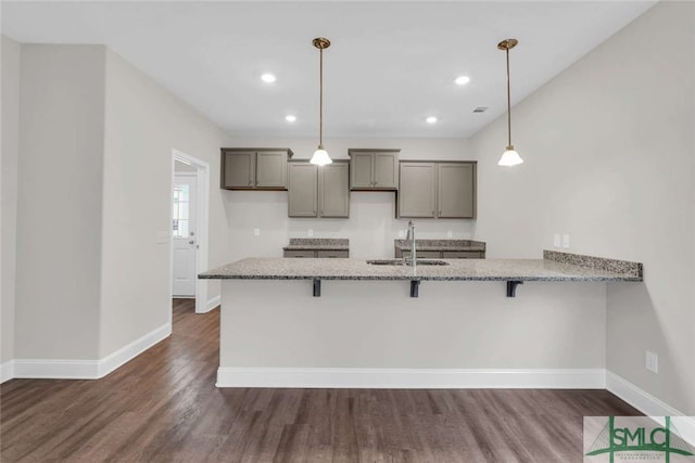 kitchen with hanging light fixtures, a kitchen breakfast bar, and dark hardwood / wood-style flooring