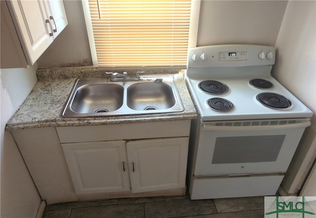 kitchen with dark tile floors, sink, white cabinetry, and white range with electric stovetop