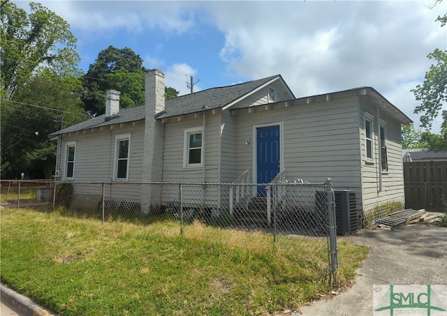 rear view of property with a yard and central air condition unit