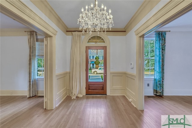 foyer entrance featuring light hardwood / wood-style floors, a notable chandelier, and ornamental molding